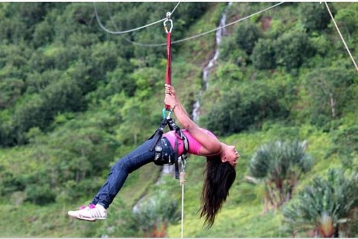 a woman hanging on to a rope on a zip line