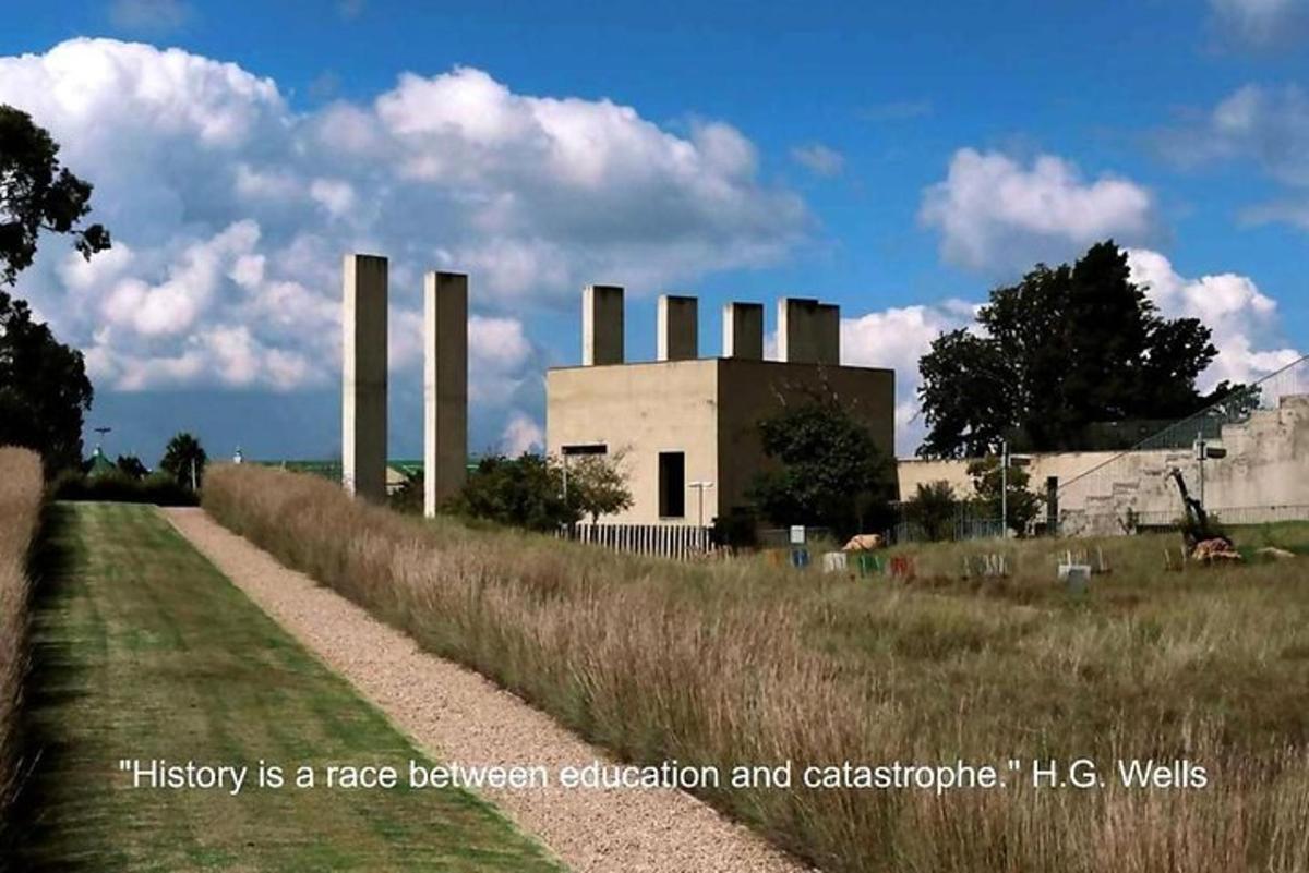 Un edificio con chimeneas al lado de un campo