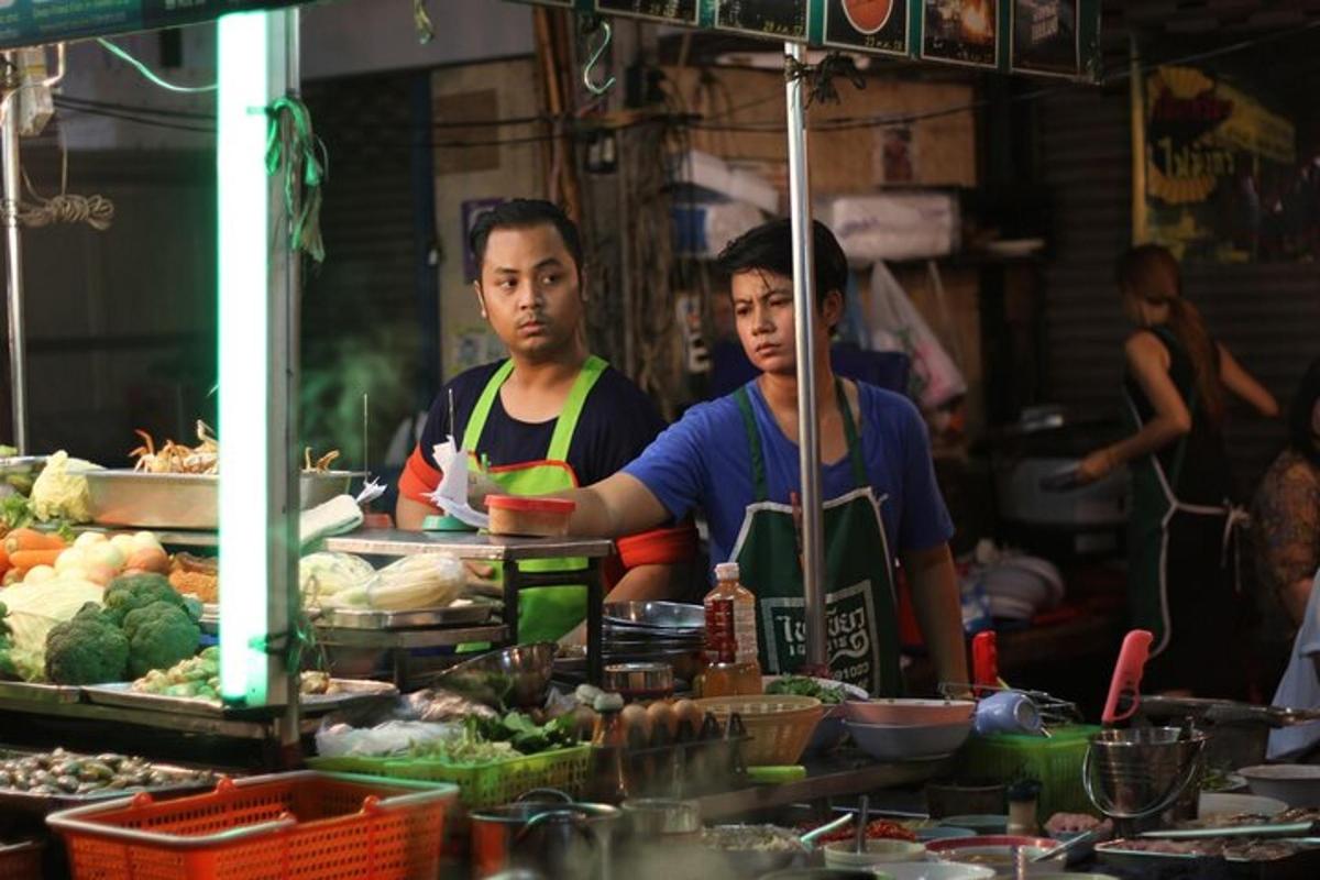 two men are standing in a market selling food
