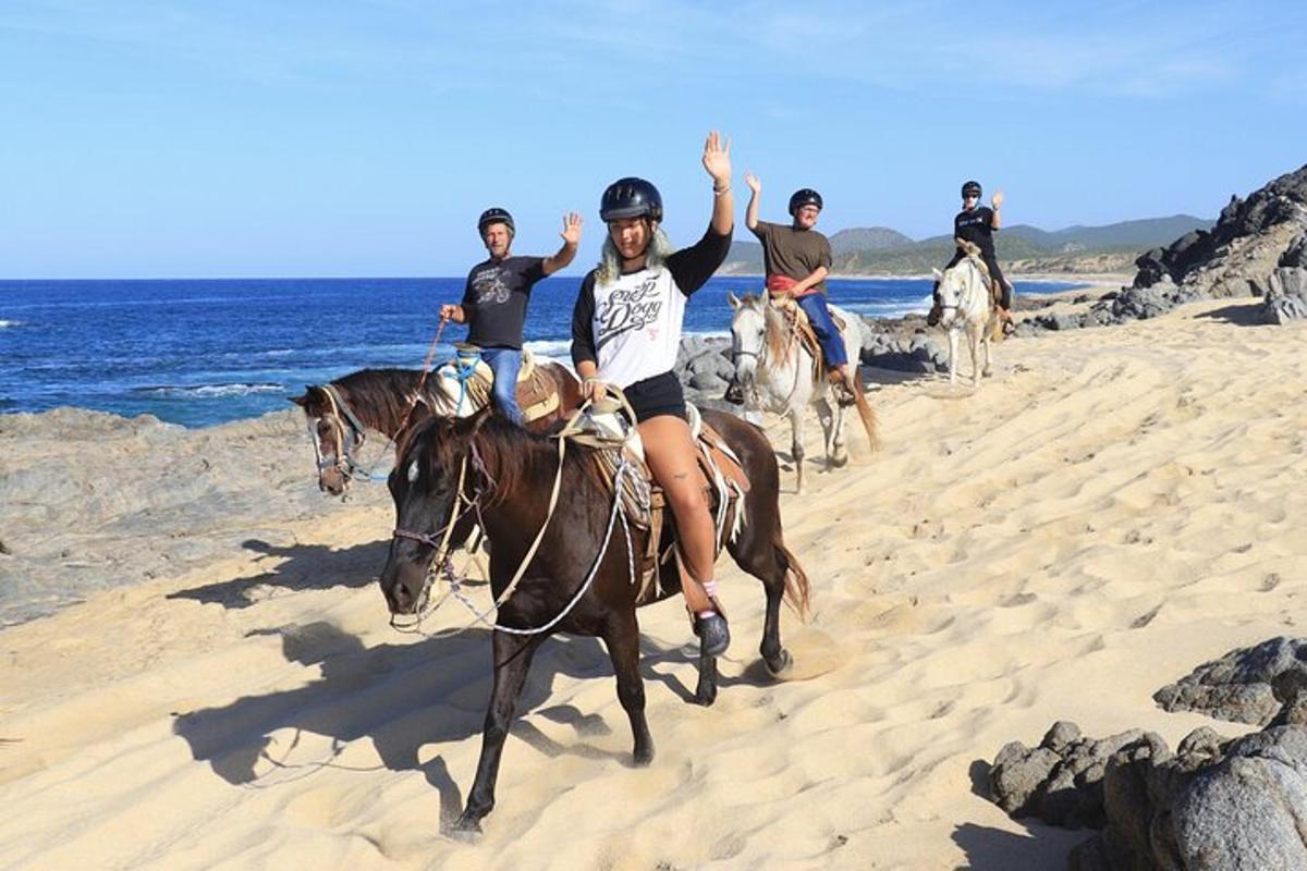 un grupo de personas montando a caballo en la playa