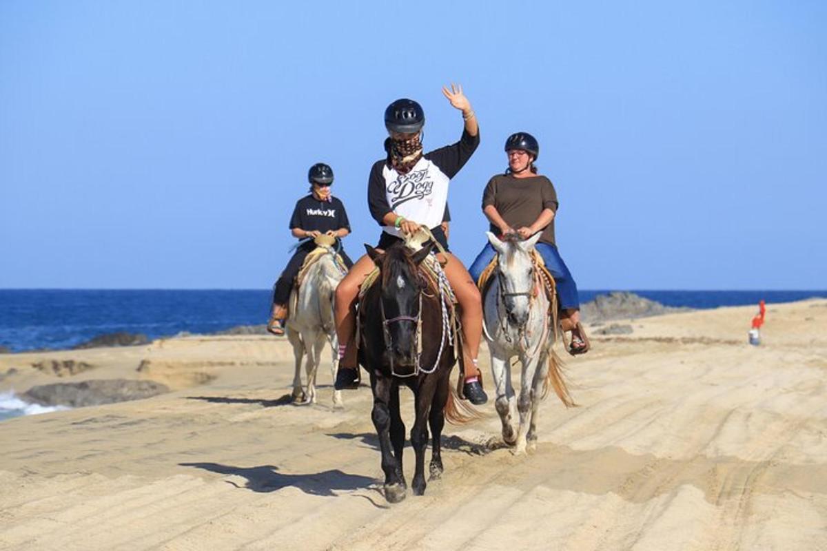 tres personas montando a caballo en la playa