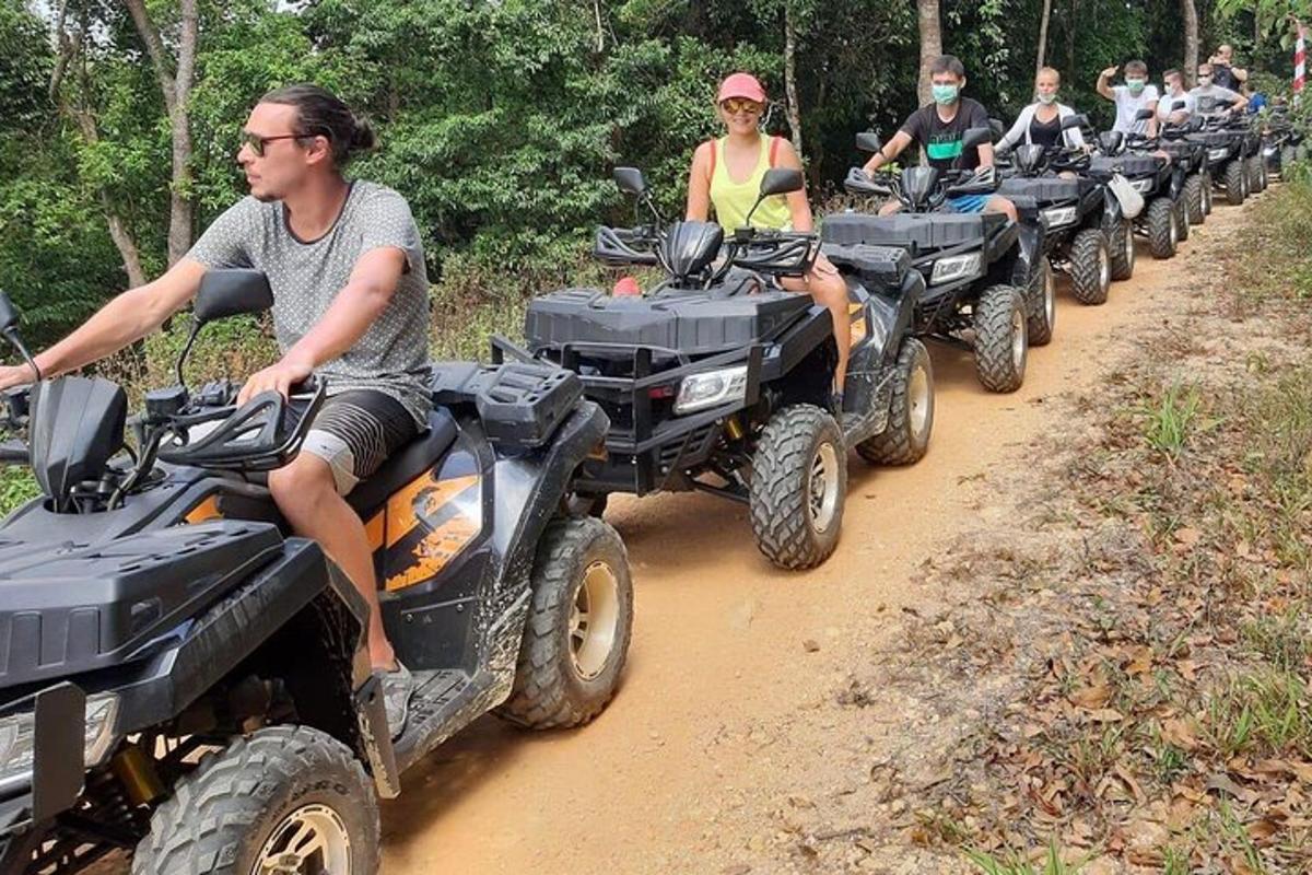 um grupo de pessoas andando de quadriciclo em uma estrada de terra