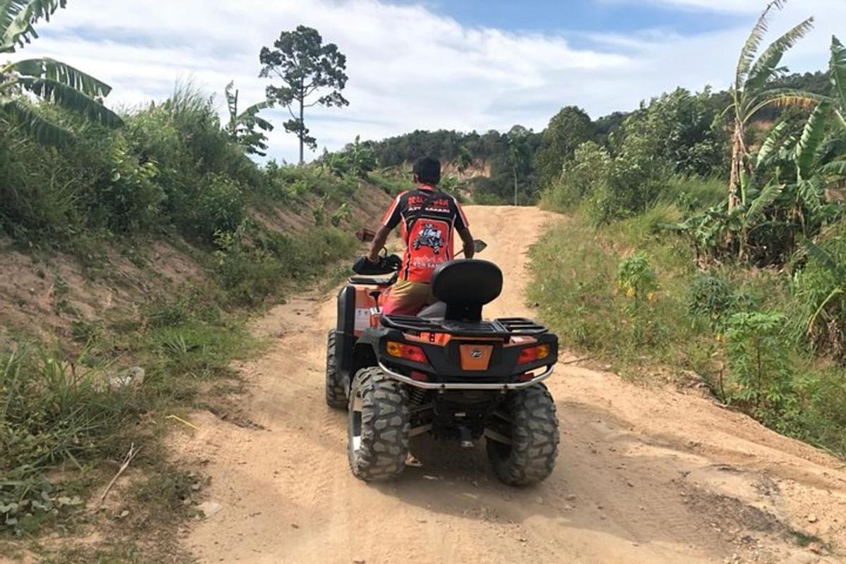 um homem andando de quadriciclo em uma estrada de terra