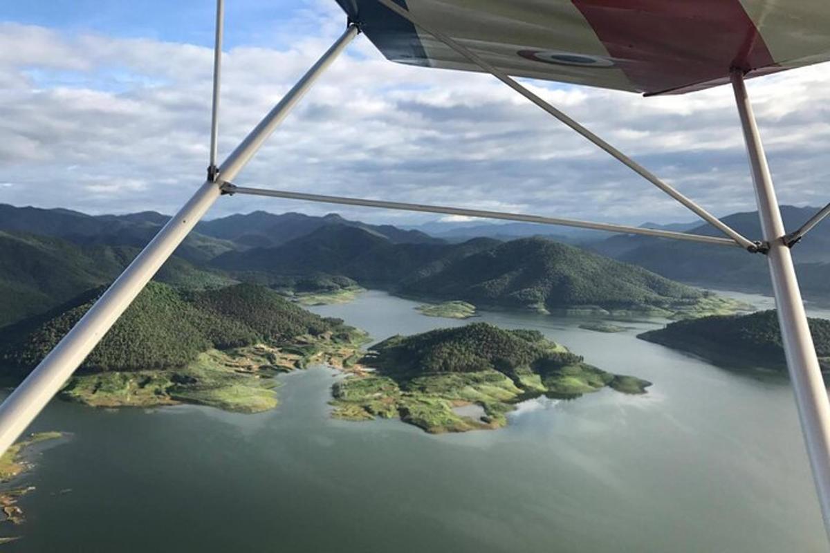 et utsyn fra vingen på et fly som flyr over en innsjø