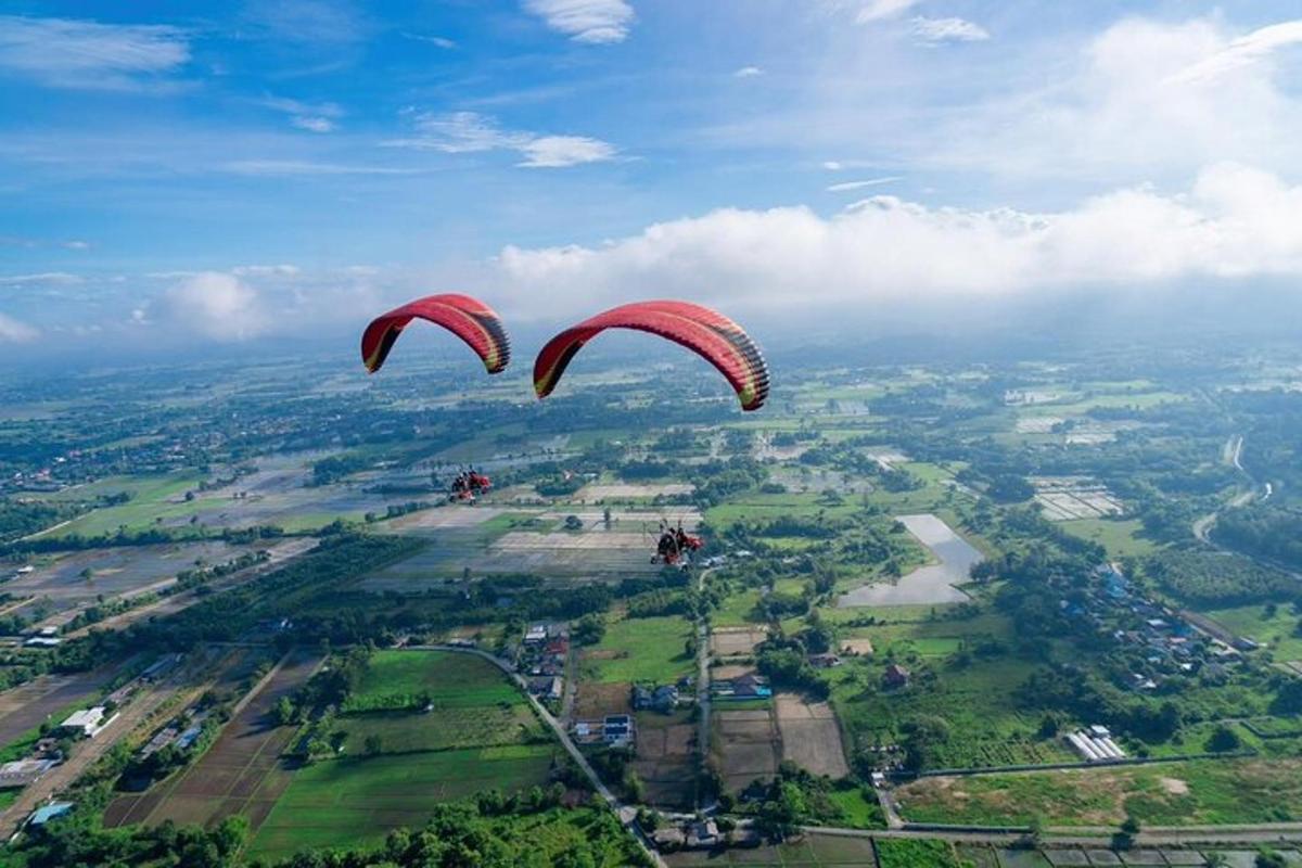 two paragliders flying in the sky over a city