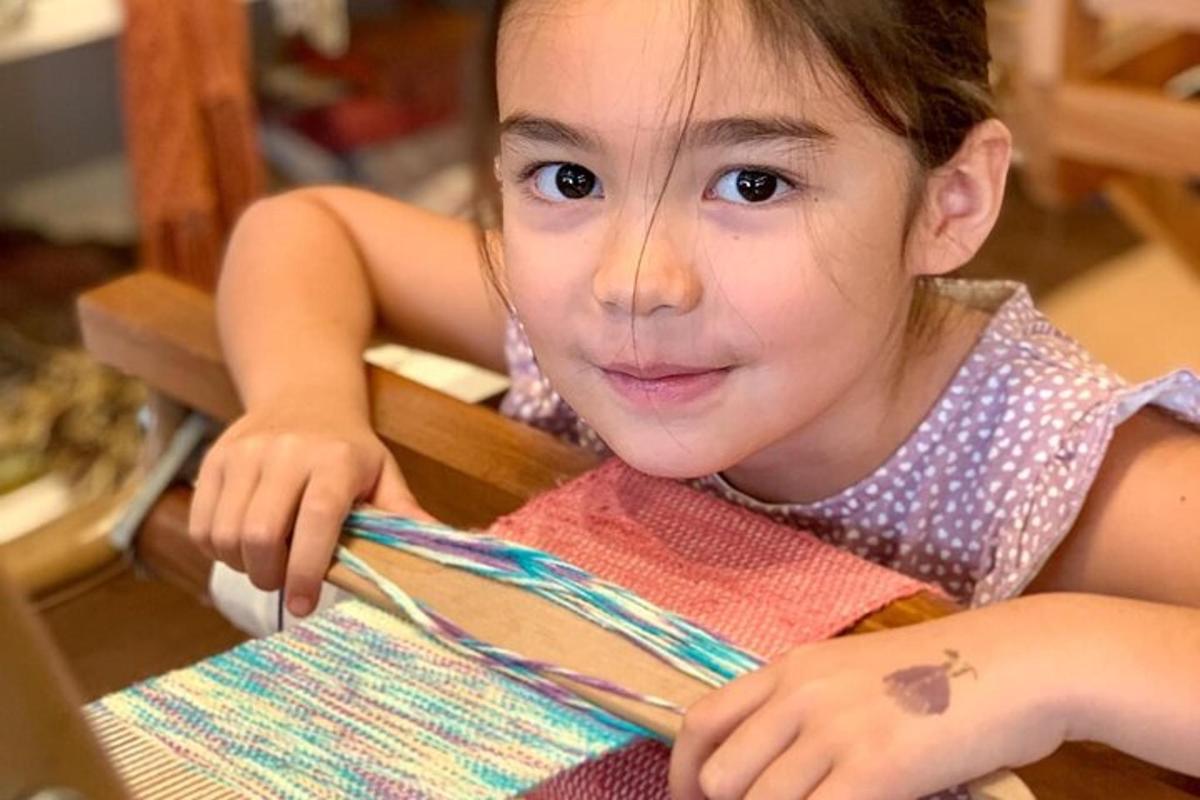 a little girl sitting at a table cutting a piece of paper