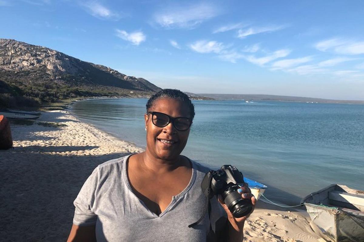 un uomo in piedi su una spiaggia con in mano una macchina fotografica