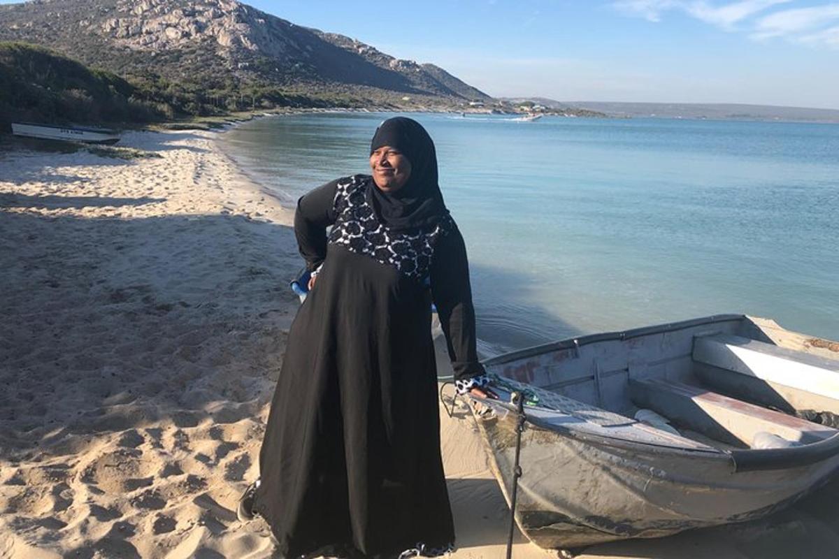 una donna in piedi accanto a una barca sulla spiaggia