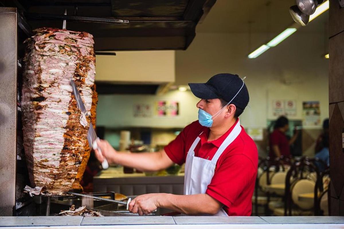 a man in a kitchen preparing a large piece of meat