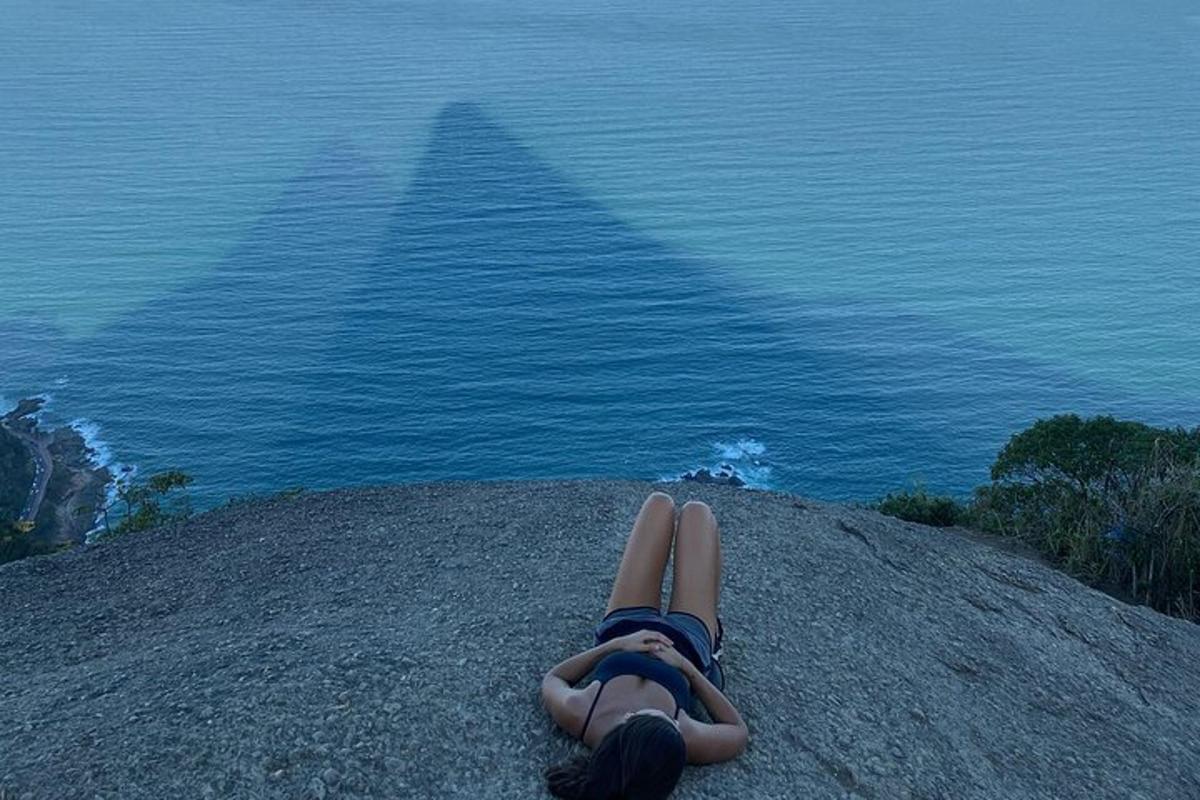 žena ležící na vrcholu kopce s výhledem na oceán