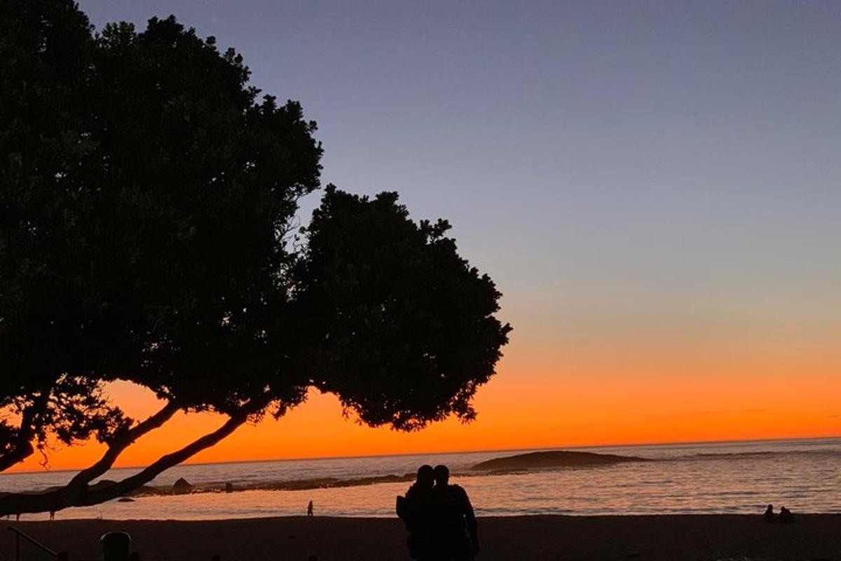 sepasang suami isteri duduk di tepi pantai sambil melihat matahari terbenam