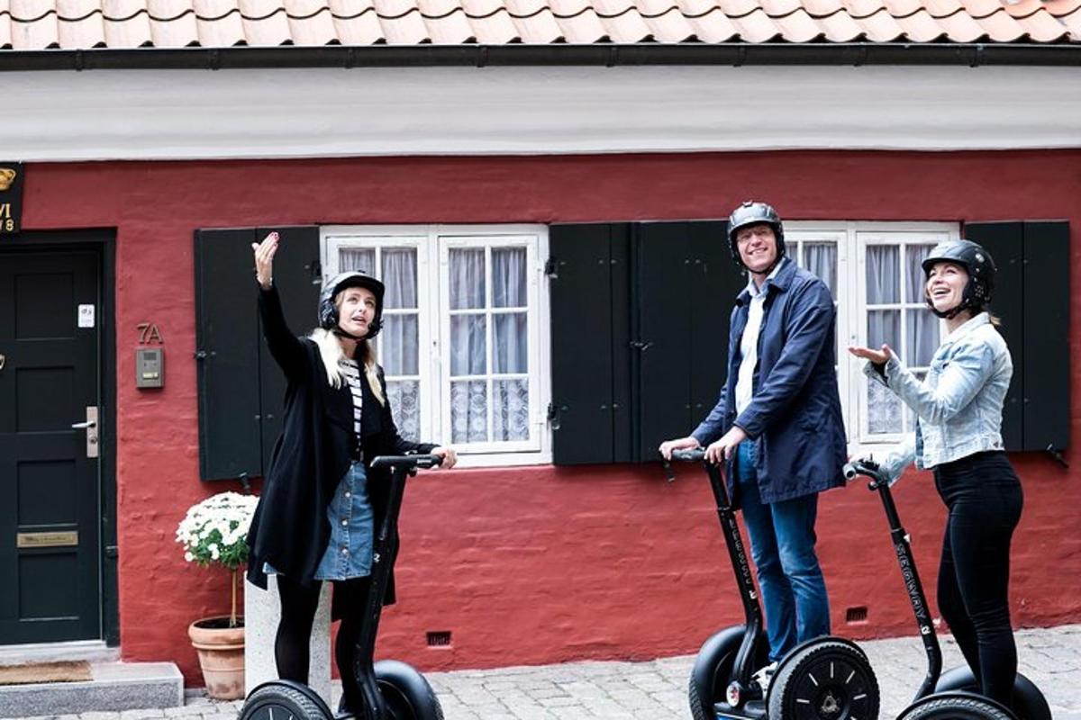 un grup de tres persones que van en segways davant d'un edifici vermell