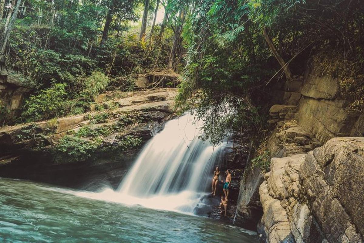 duas pessoas em pé em frente a uma cachoeira