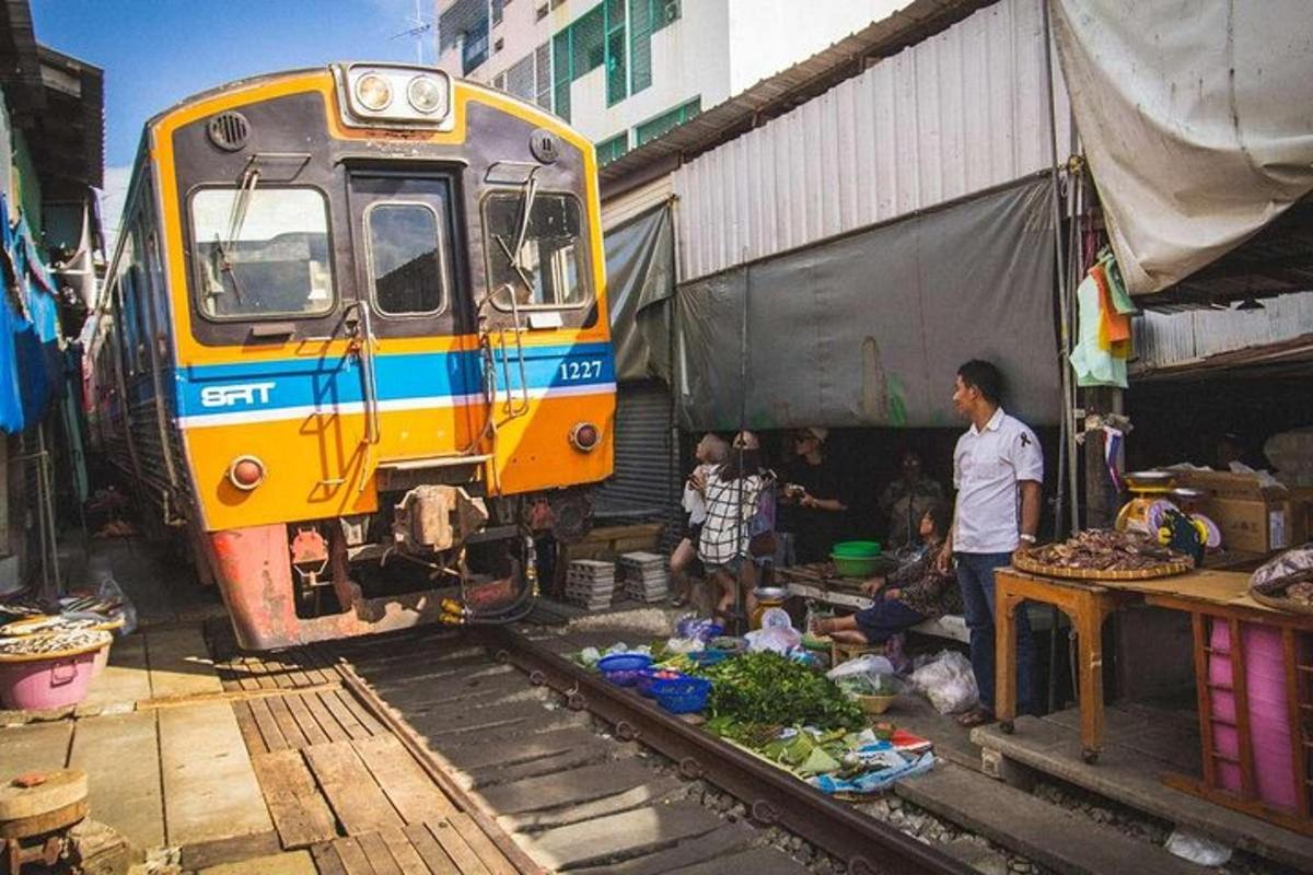 รถไฟจอดอยู่ข้างตลาดที่มีคนกลุ่มหนึ่งอยู่