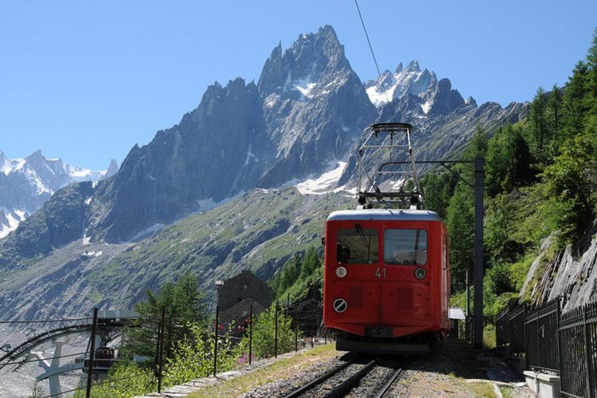 a red train on the tracks with mountains in the background