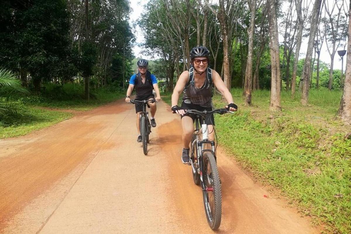 two people riding bikes down a dirt road