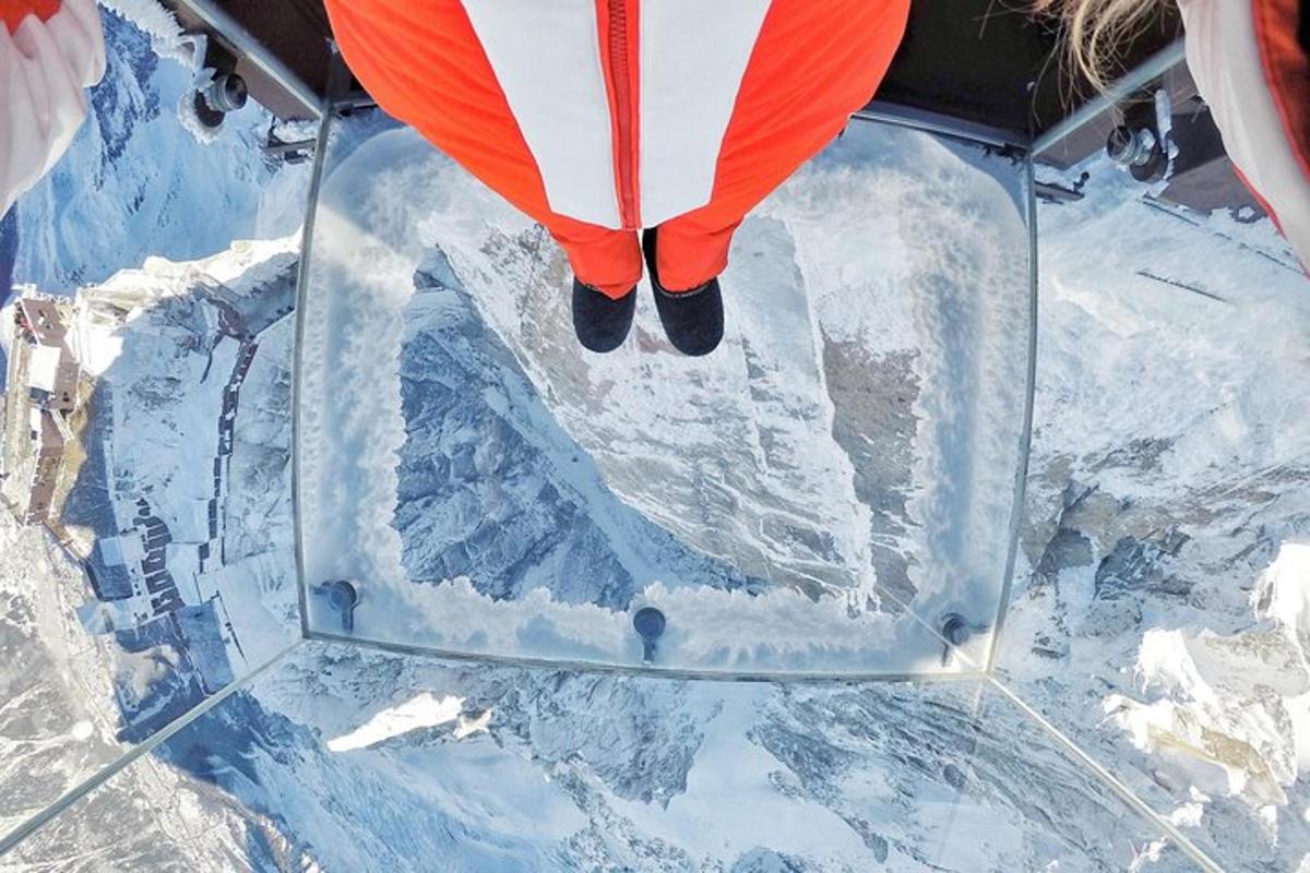 an aerial view of a person flying over snow covered mountains