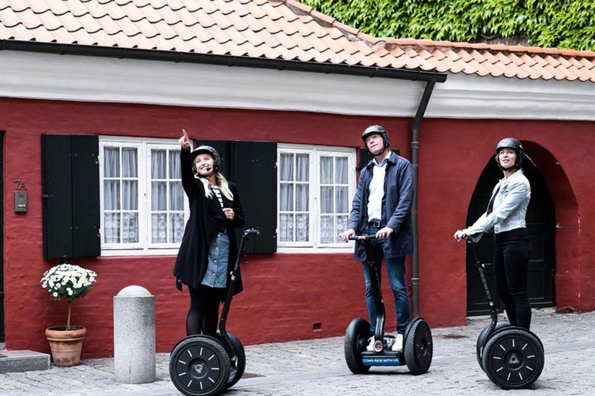 trije ljudje se vozijo na segwayih pred rdečo stavbo