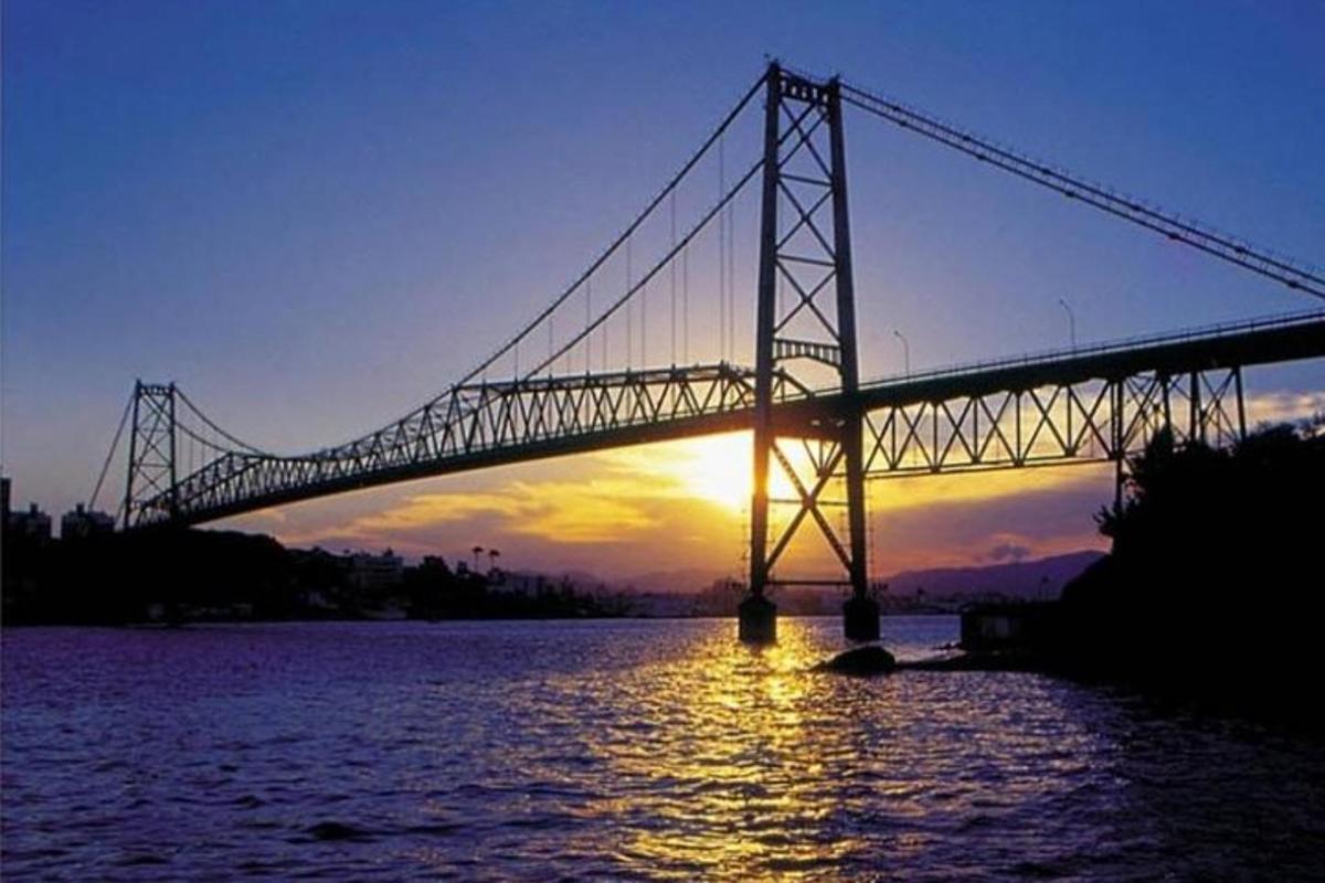 uma ponte sobre um rio com o sol se pondo atrás dela