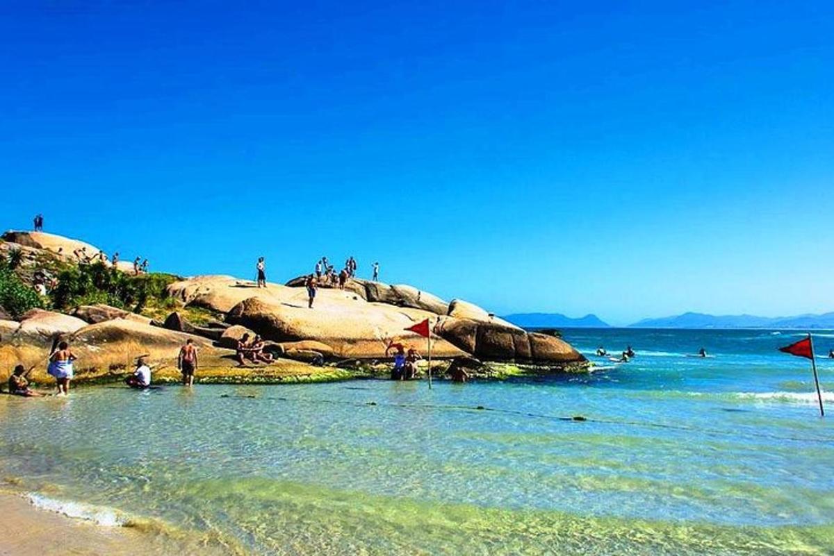 um grupo de pessoas sentadas em pedras na praia