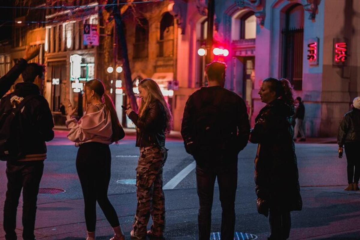 un gruppo di persone in attesa di attraversare la strada di notte