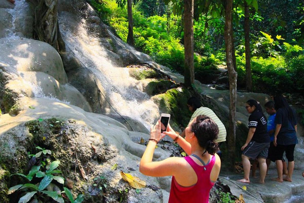 eine Frau, die mit ihrem Handy ein Foto von einem Wasserfall macht