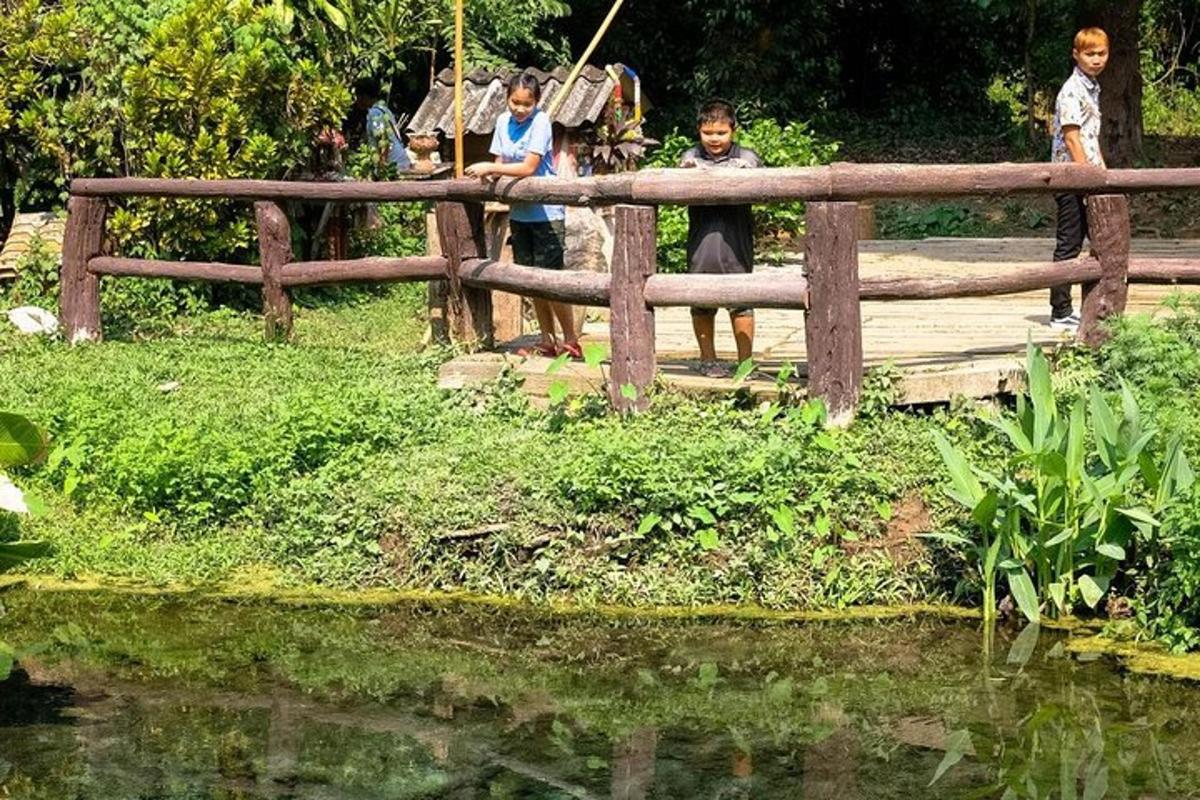 tři děti stojící na dřevěném mostě přes rybník
