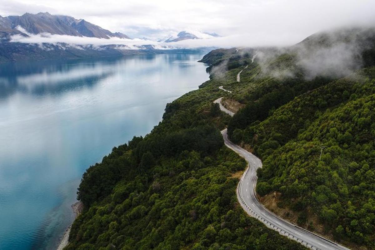 an aerial view of a road next to a lake