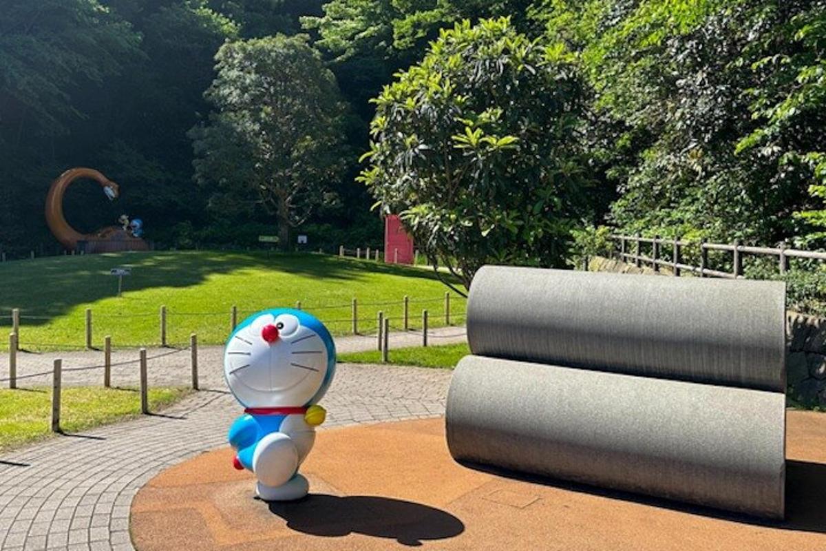 a teddy bear standing next to a sculpture in a park