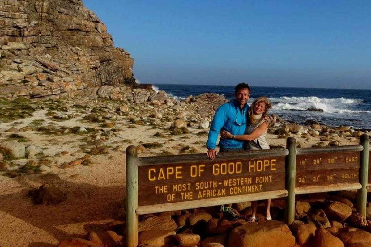 Un hombre y una mujer de pie junto a un cartel en la playa.