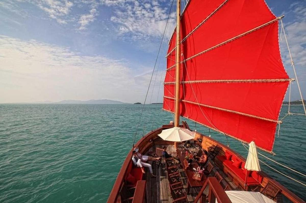 a boat with a red sail in the water