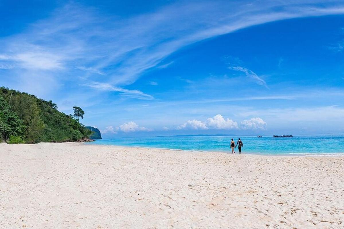 dues persones caminant per una platja a prop de l'oceà