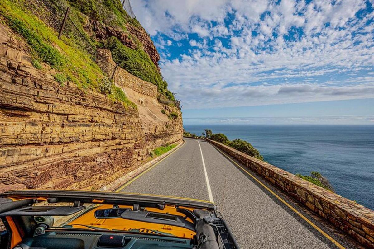 un'auto che percorre una strada vicino all'oceano