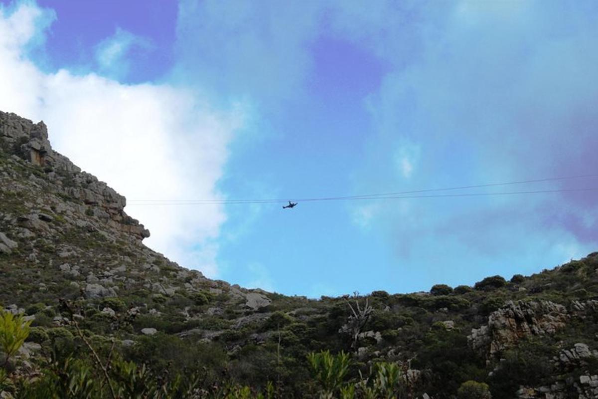 un aereo che vola sopra una collina con un cielo azzurro