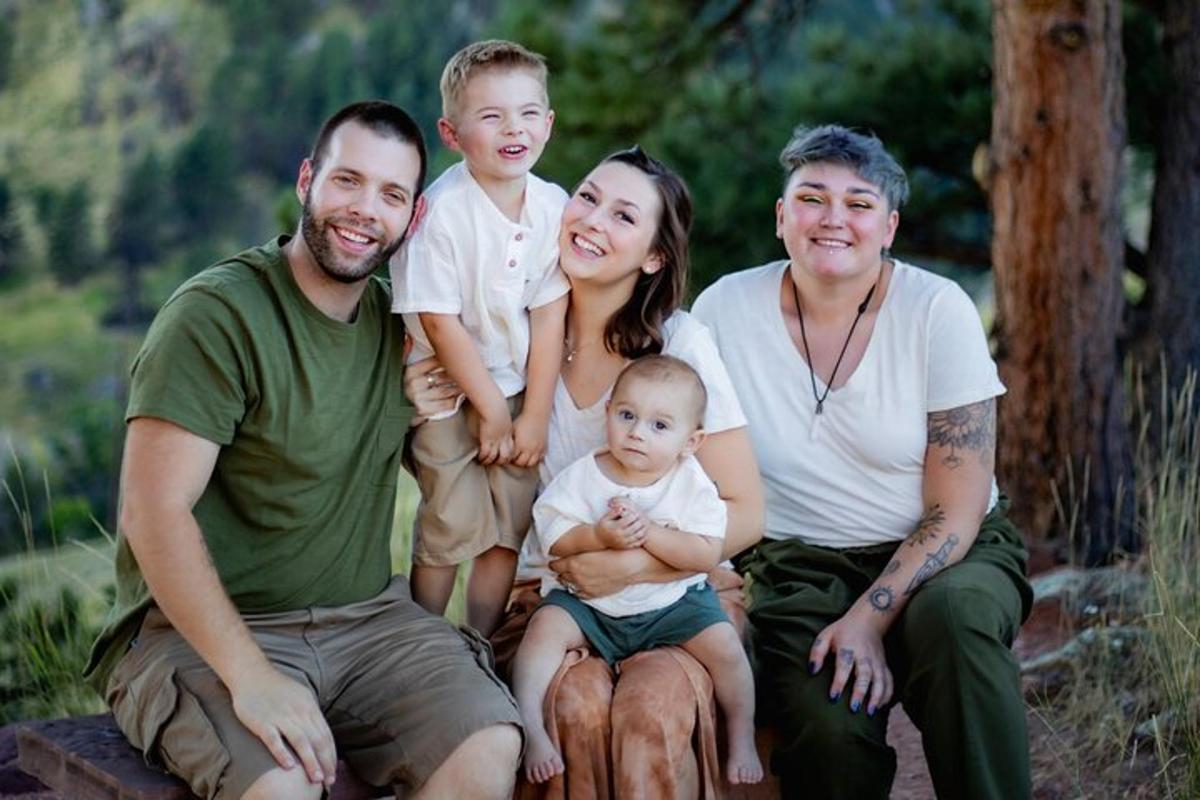 Una familia posa para una fotografía mientras sostiene a un bebé.