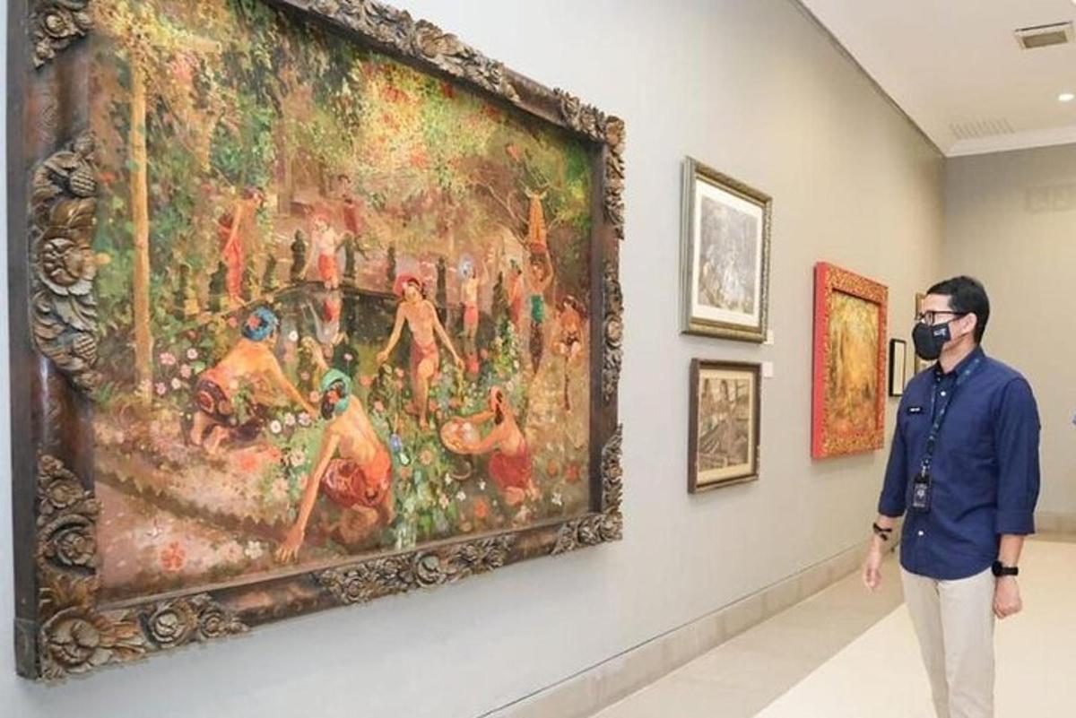 a man wearing a mask standing in front of a painting