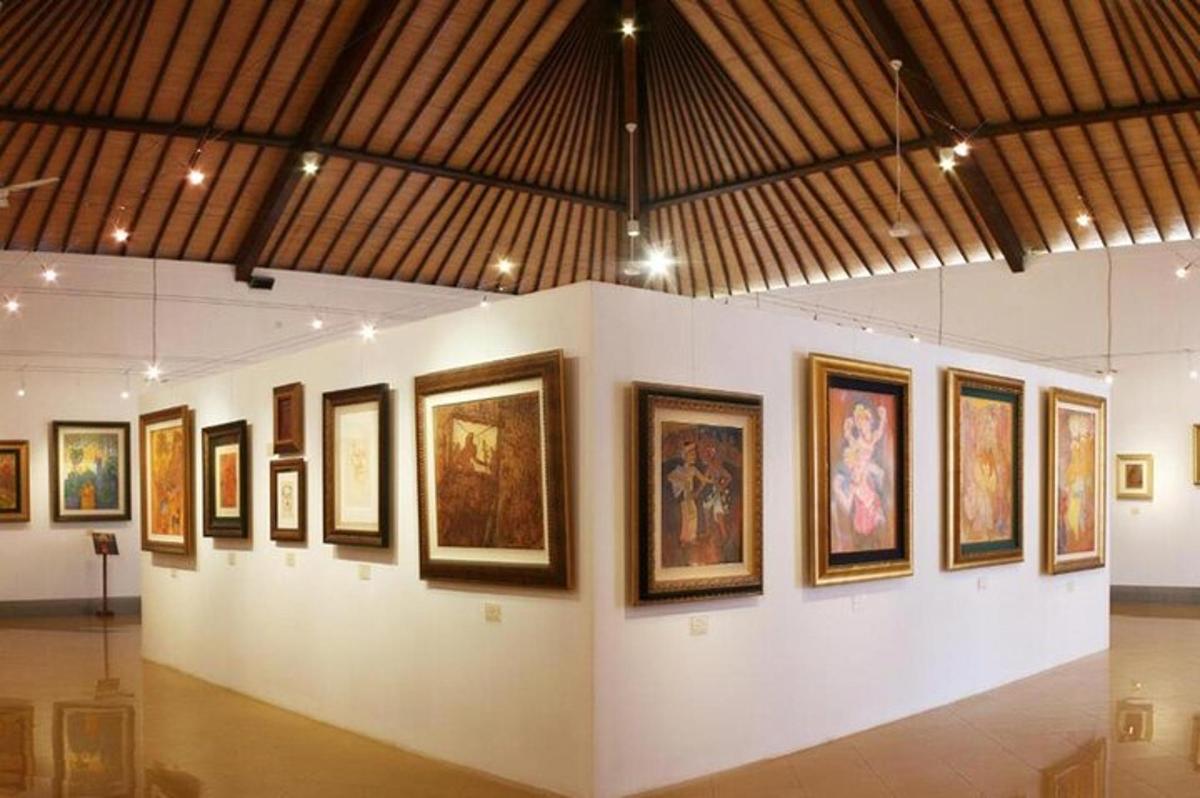 a group of framed paintings on a wall in a museum