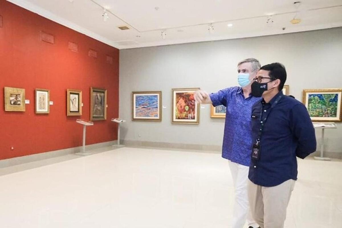 two men standing in a room looking at art