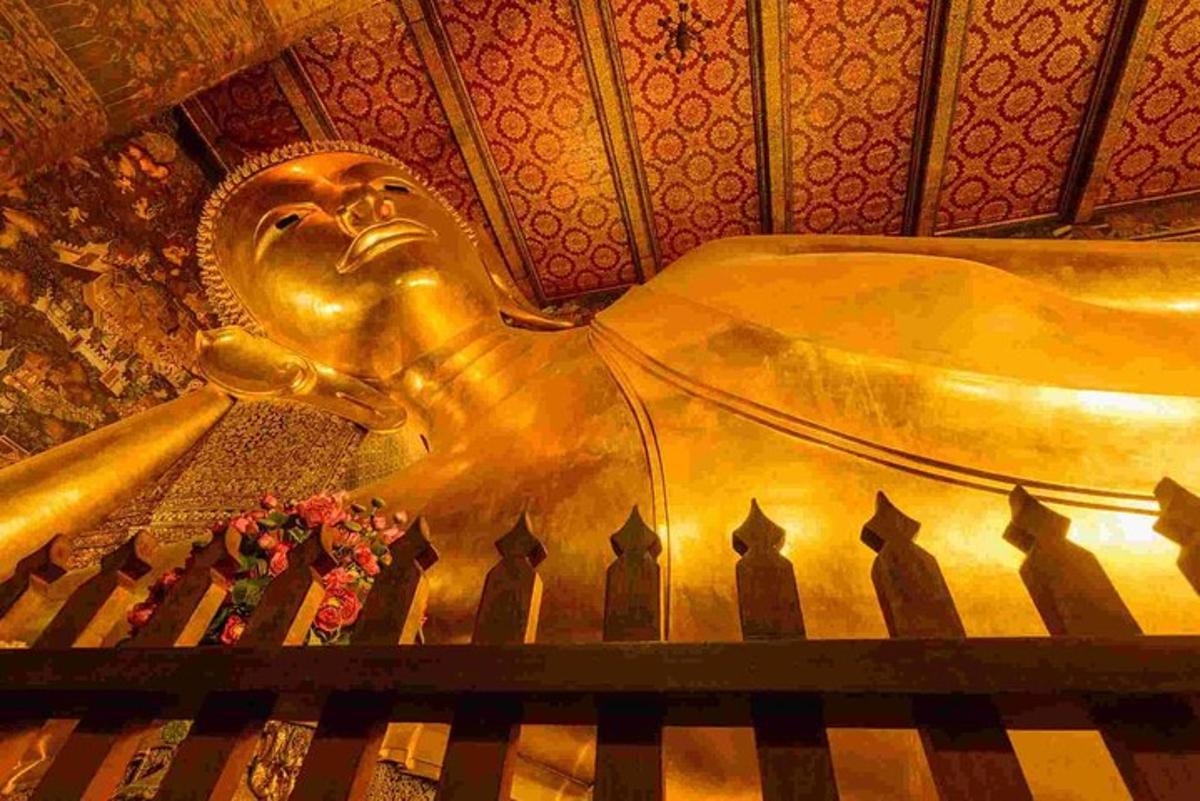 una statua dorata di un Buddha seduto accanto a un pianoforte