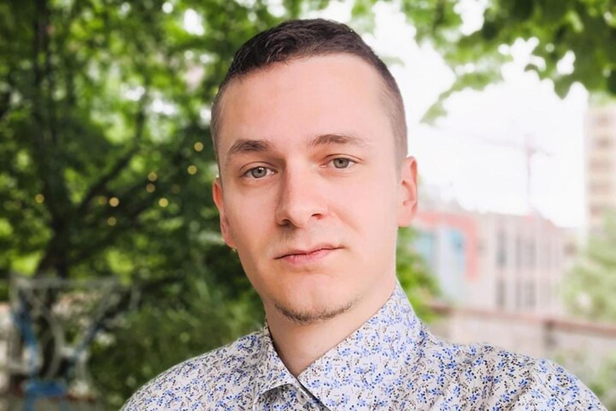 чоловік у синій сорочці дивиться в камеру