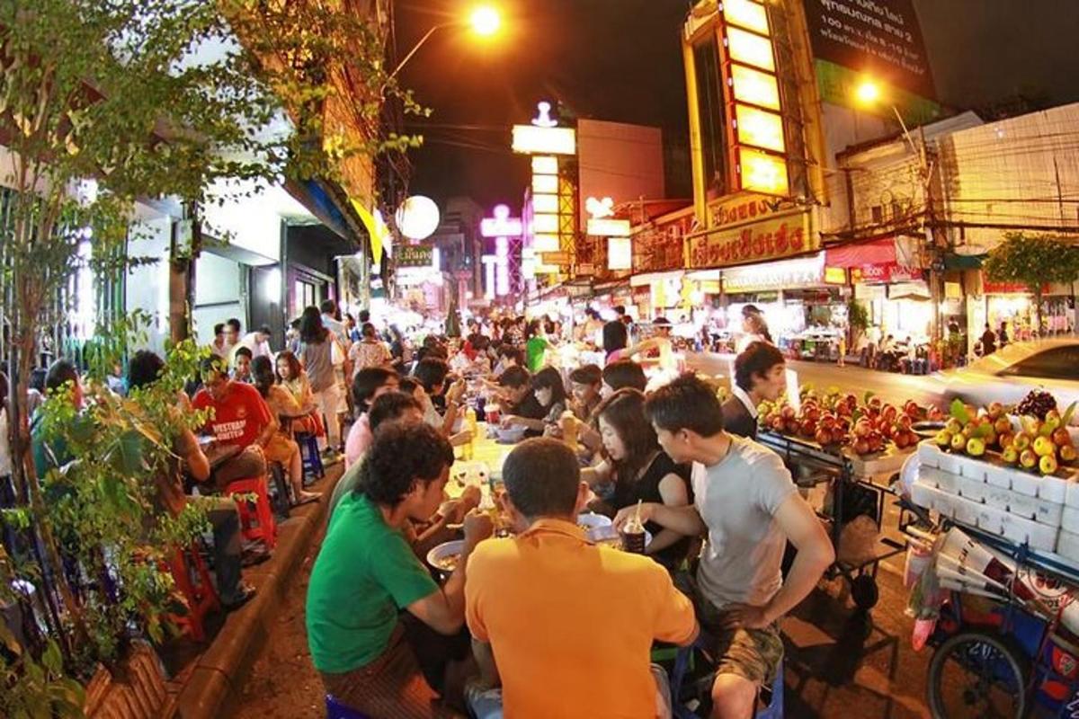 una folla di persone sedute ai tavoli in una strada di notte