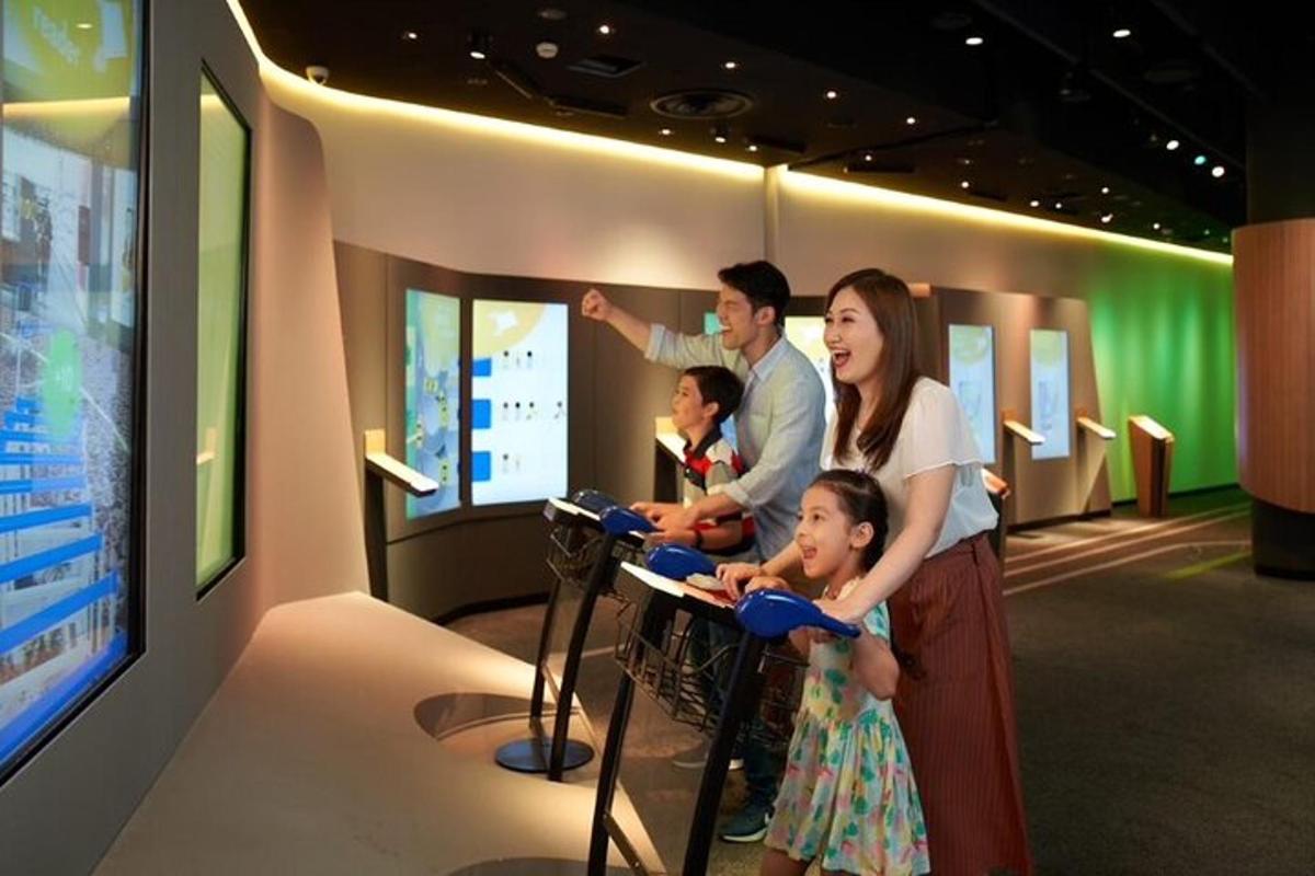 sebuah keluarga berdiri di hadapan tv di sebuah muzium