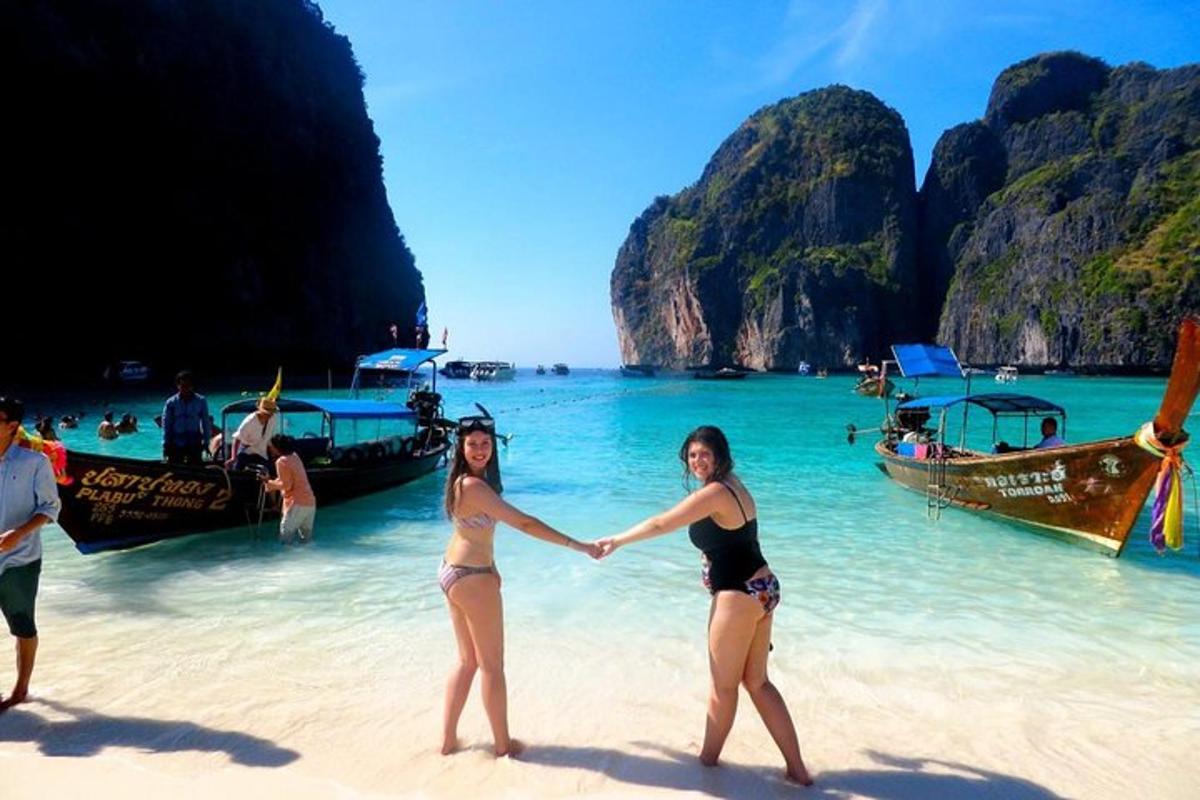 dve ženski, ki stojita na plaži in se držita za roke