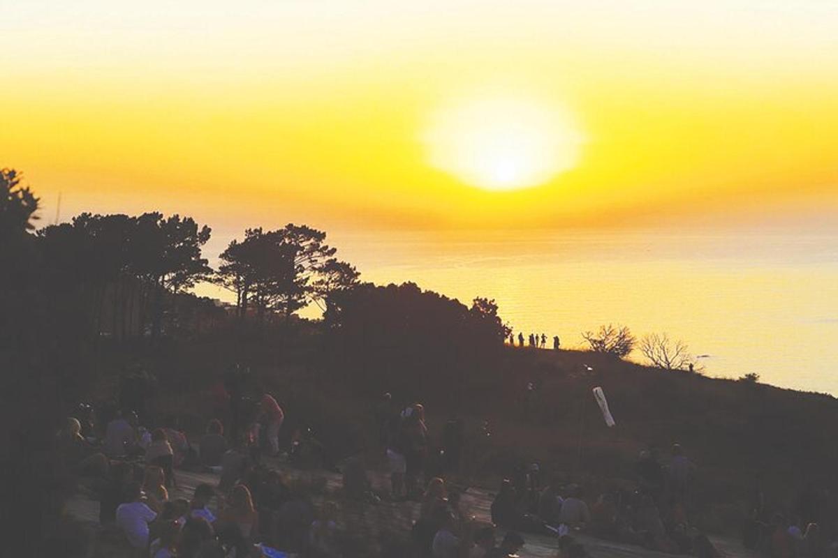 un gruppo di persone sedute su una collina al tramonto