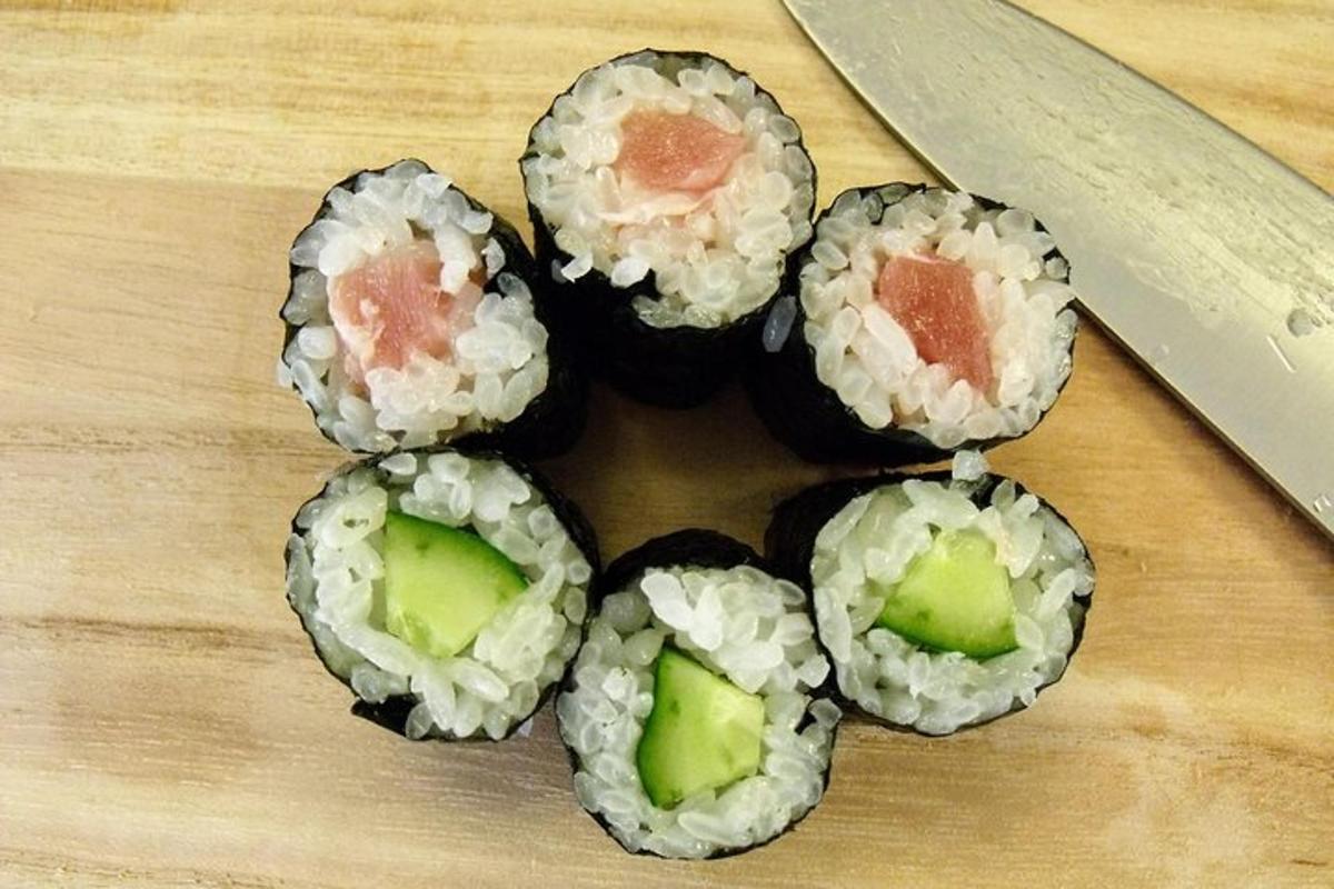 čtyři sushi rolky na prkénku s nožem