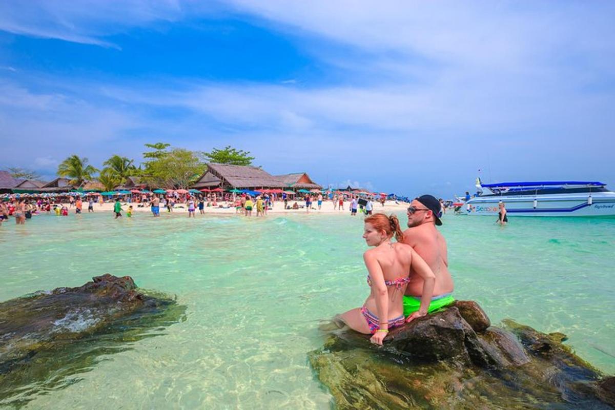um casal sentado em pedras na água de uma praia