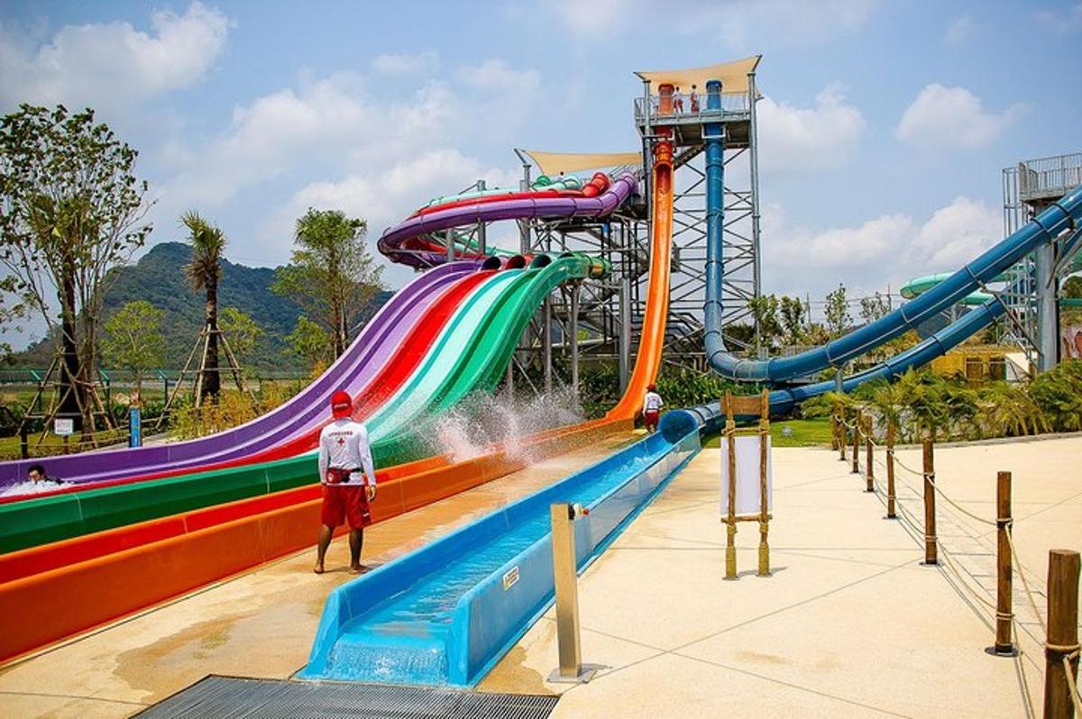 a man standing in front of a water slide at a water park