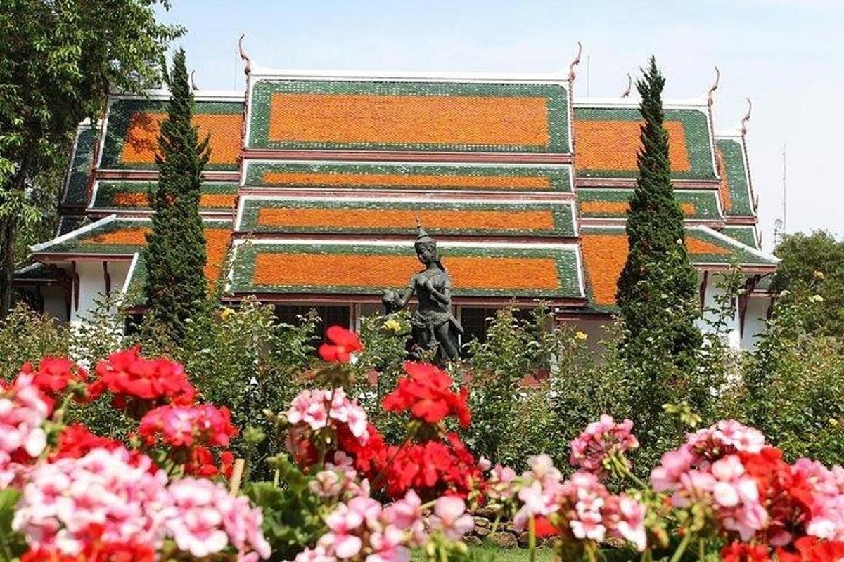 una statua in un giardino con fiori di fronte a un edificio