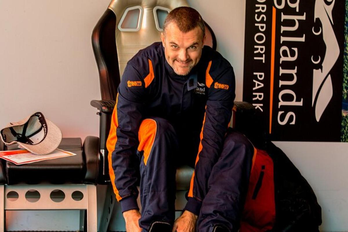maður situr í stól með fótinn á tösku