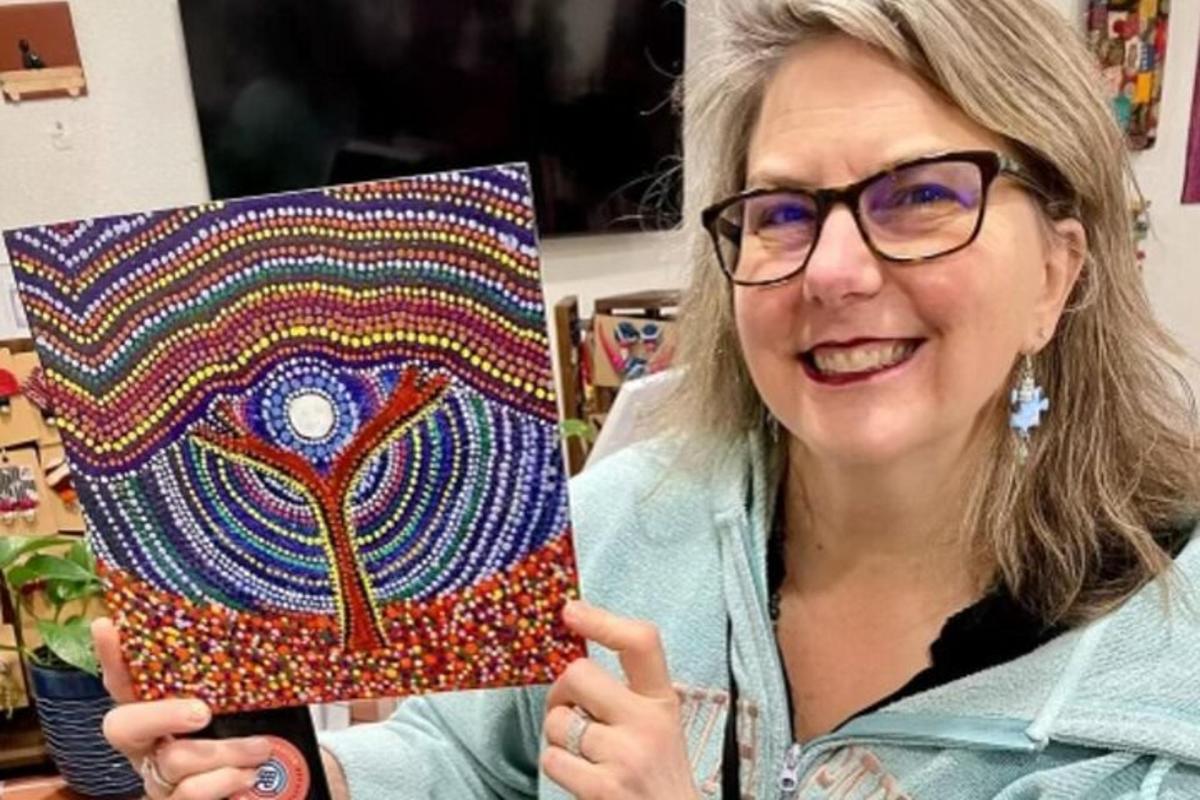 a woman holding up a painting of a peacock